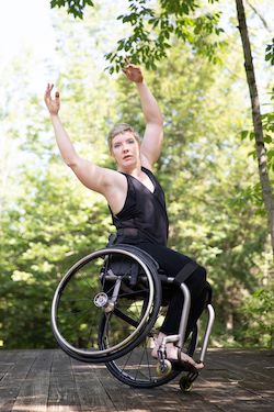 Laurel Lawson balances on one wheel, tilting away from the camera. She throws her arms overhead and looks at the viewer. Photo by Hayim Heron, courtesy of Jacob's Pillow.