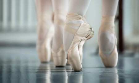 Dancers en pointe on a Marley dance floor.