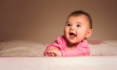 smiling baby lying on bed in room