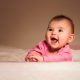 smiling baby lying on bed in room