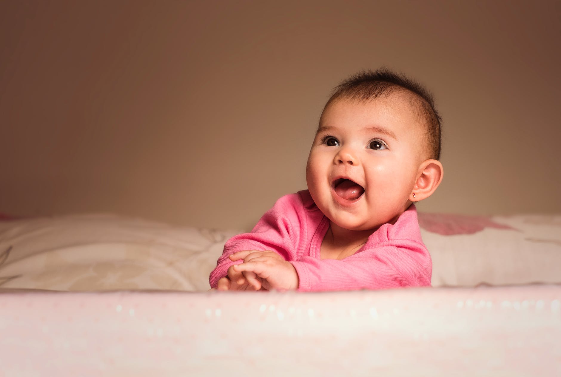 smiling baby lying on bed in room