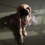 unrecognizable graceful ballet dancer resting on floor