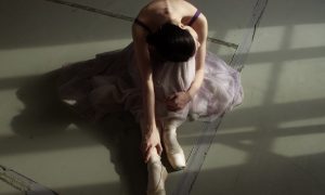 unrecognizable graceful ballet dancer resting on floor