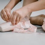 crop faceless ballerina girl tying straps of pointe shoes