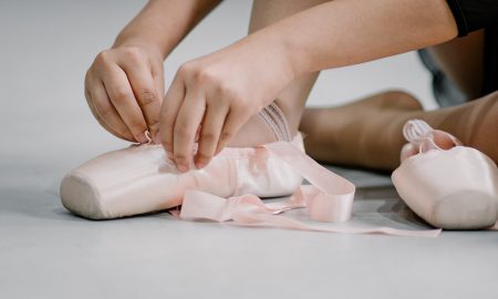 crop faceless ballerina girl tying straps of pointe shoes