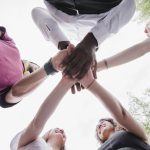 A group of people holding hands together. Photo by Freepik.