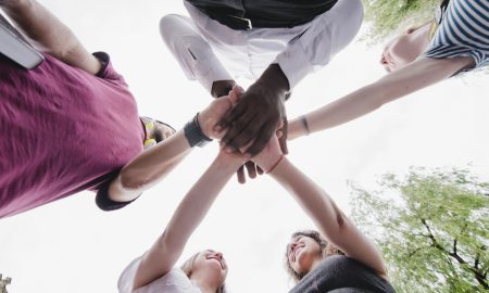 A group of people holding hands together. Photo by Freepik.