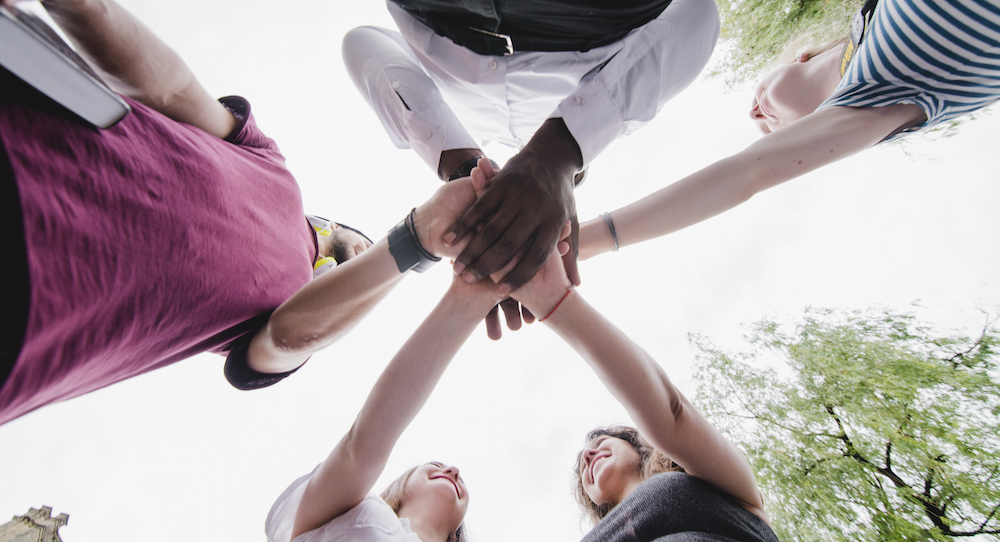 A group of people holding hands together. Photo by Freepik.