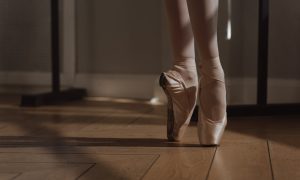a person wearing ballet shoes on a wooden floor
