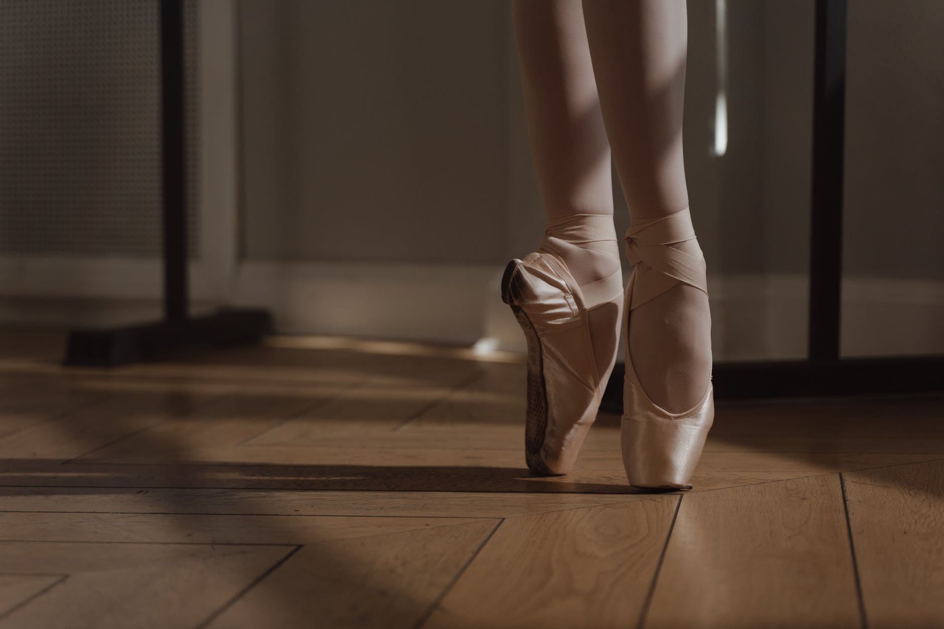 a person wearing ballet shoes on a wooden floor