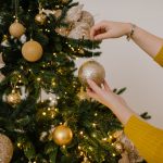 close up shot of a person putting christmas balls on a christmas tree