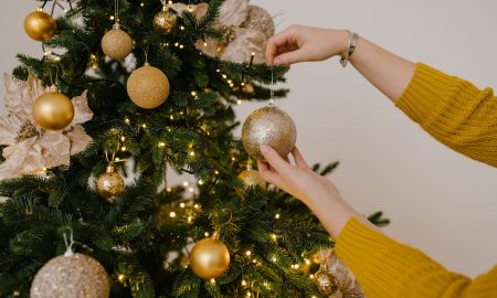 close up shot of a person putting christmas balls on a christmas tree