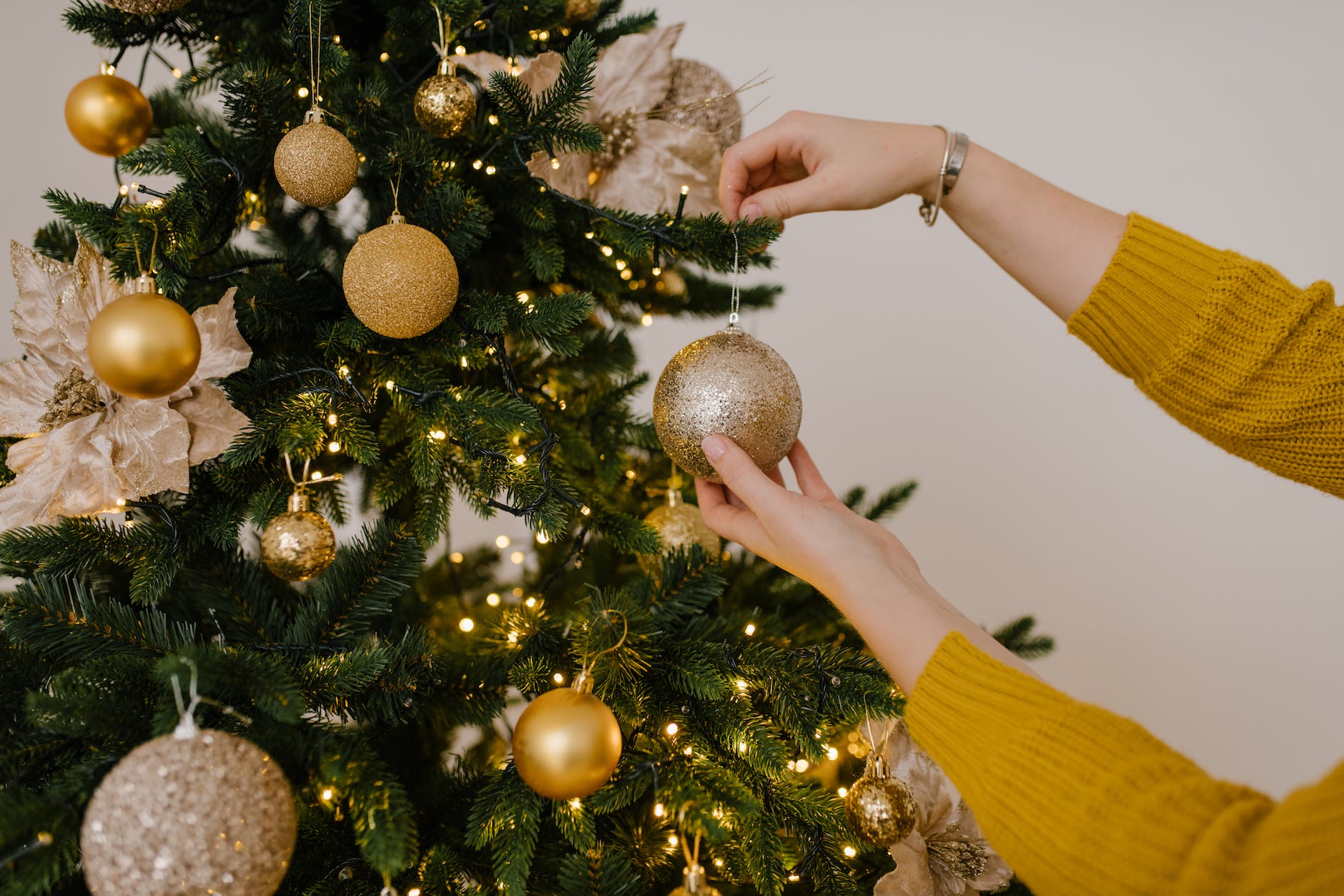 close up shot of a person putting christmas balls on a christmas tree